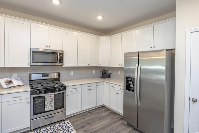 kitchen with decorative backsplash, white cabinetry, dark hardwood / wood-style flooring, and appliances with stainless steel finishes