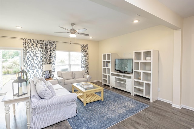 living room with plenty of natural light, dark wood-type flooring, and ceiling fan