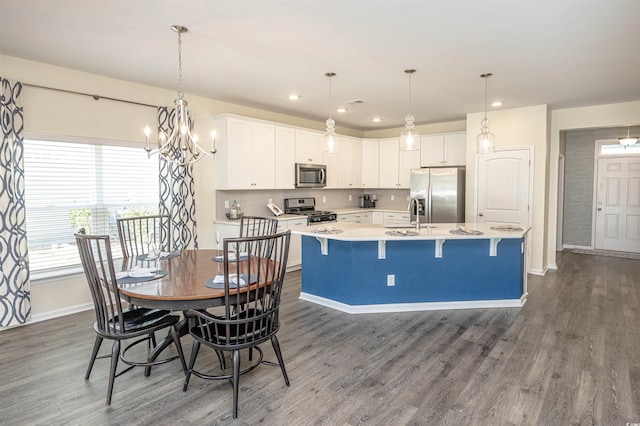 kitchen with pendant lighting, dark hardwood / wood-style floors, white cabinetry, and appliances with stainless steel finishes