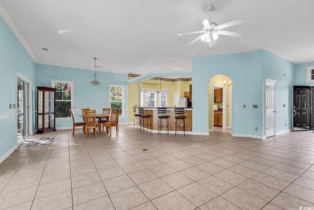 interior space featuring a wealth of natural light, light tile patterned floors, and ceiling fan with notable chandelier