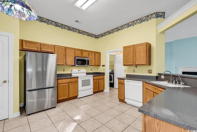 kitchen with sink, kitchen peninsula, washer / clothes dryer, light tile patterned flooring, and appliances with stainless steel finishes