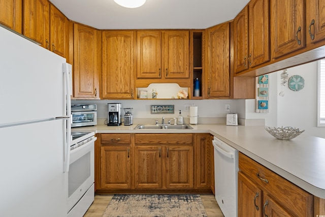 kitchen with kitchen peninsula, white appliances, light hardwood / wood-style flooring, and sink