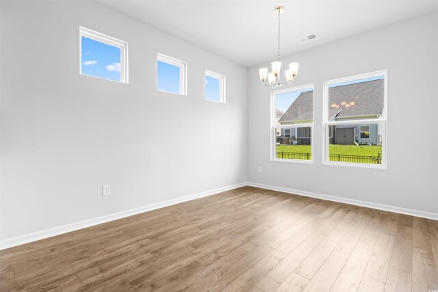 spare room with a chandelier and hardwood / wood-style floors