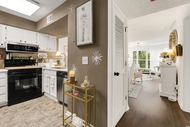 kitchen featuring white cabinets, appliances with stainless steel finishes, a textured ceiling, and light hardwood / wood-style flooring