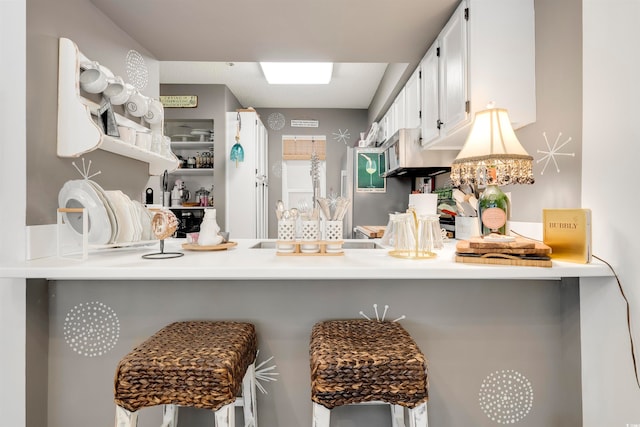 kitchen featuring a kitchen bar, kitchen peninsula, and white cabinets