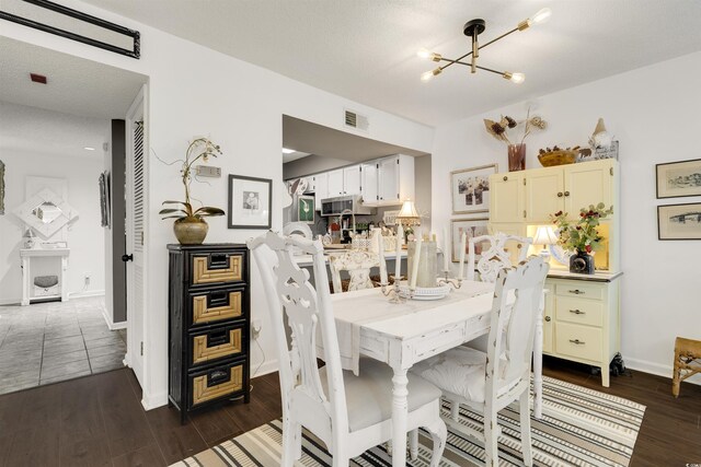 dining area featuring a textured ceiling, a chandelier, and dark hardwood / wood-style floors