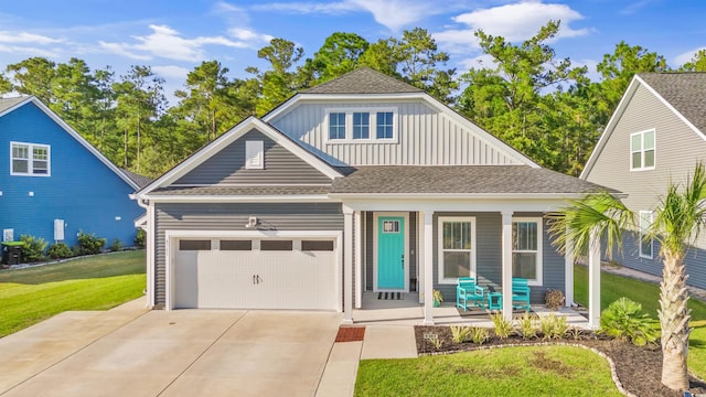 view of front of home featuring covered porch, a garage, and a front yard