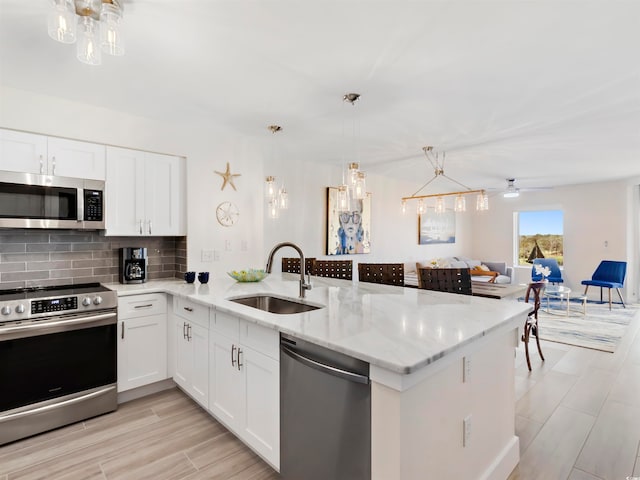 kitchen with kitchen peninsula, stainless steel appliances, white cabinetry, and sink