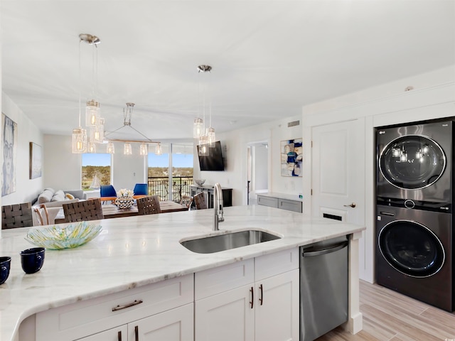 kitchen featuring light stone countertops, stainless steel dishwasher, sink, light hardwood / wood-style flooring, and stacked washer and clothes dryer