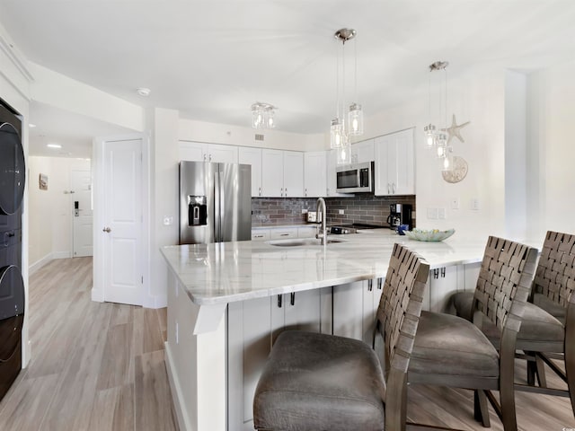 kitchen with a breakfast bar, hanging light fixtures, kitchen peninsula, appliances with stainless steel finishes, and white cabinetry