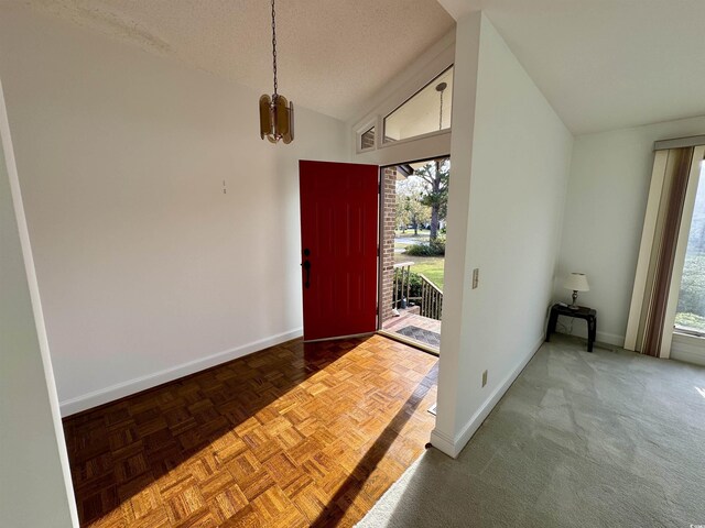 entrance foyer featuring baseboards, vaulted ceiling, and a textured ceiling