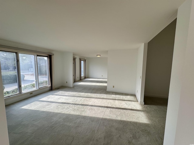 unfurnished room featuring light colored carpet and baseboards