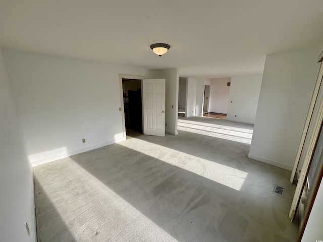 spare room with baseboards, visible vents, and light colored carpet