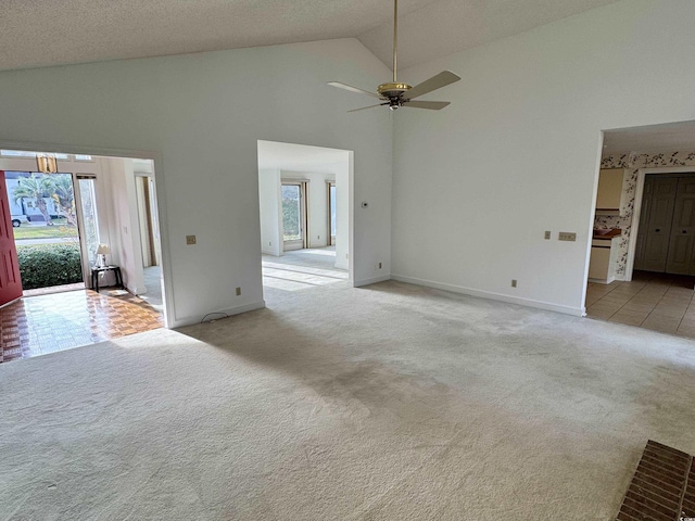 unfurnished living room featuring a healthy amount of sunlight, baseboards, high vaulted ceiling, and light colored carpet