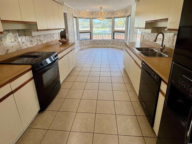 kitchen featuring black electric range oven, refrigerator, light tile patterned floors, and cream cabinets