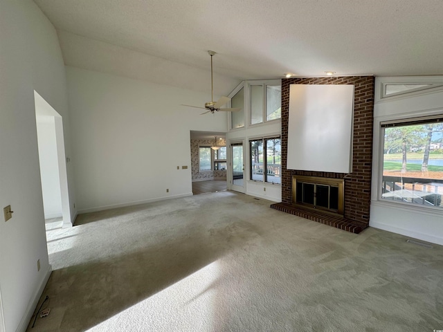 unfurnished living room with ceiling fan, high vaulted ceiling, carpet flooring, baseboards, and a brick fireplace