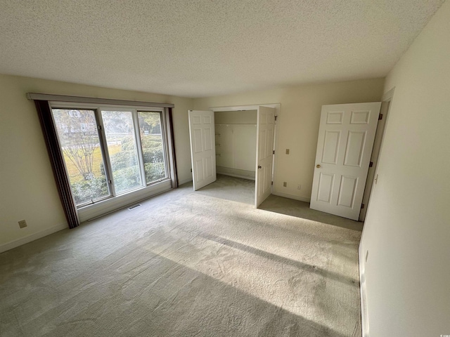 unfurnished bedroom featuring a textured ceiling, carpet, visible vents, and baseboards