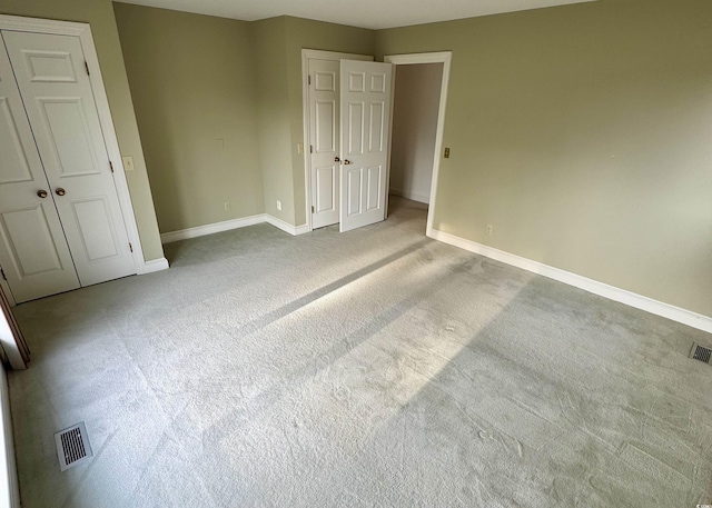 unfurnished bedroom featuring carpet flooring, visible vents, and baseboards