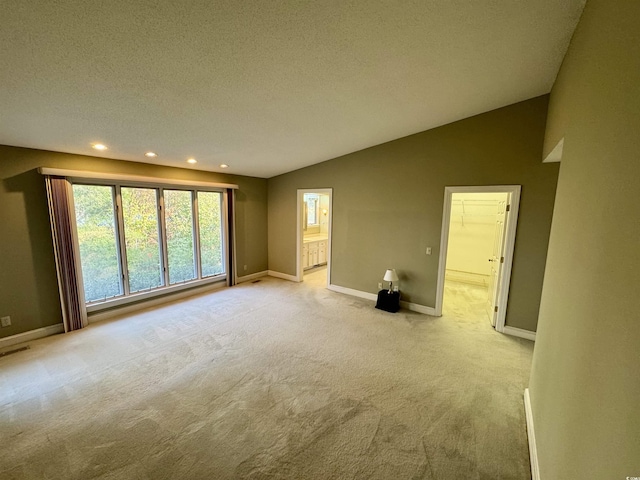 unfurnished room featuring lofted ceiling, recessed lighting, light colored carpet, a textured ceiling, and baseboards