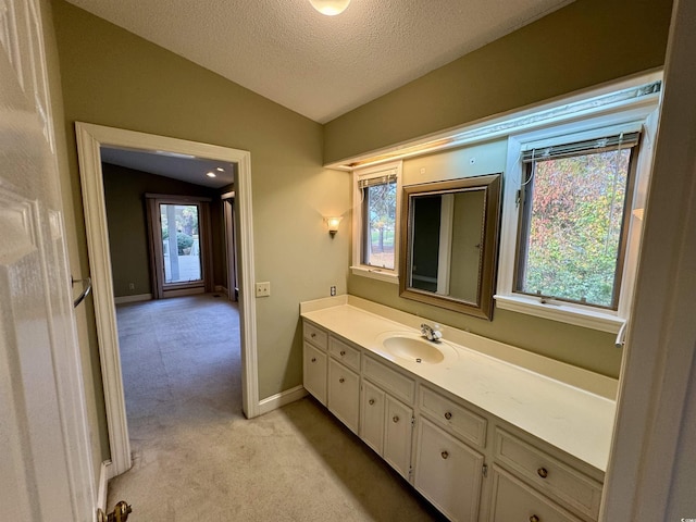 bathroom with a textured ceiling, vanity, and vaulted ceiling