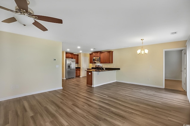 unfurnished living room with ceiling fan with notable chandelier, dark wood-type flooring, and sink