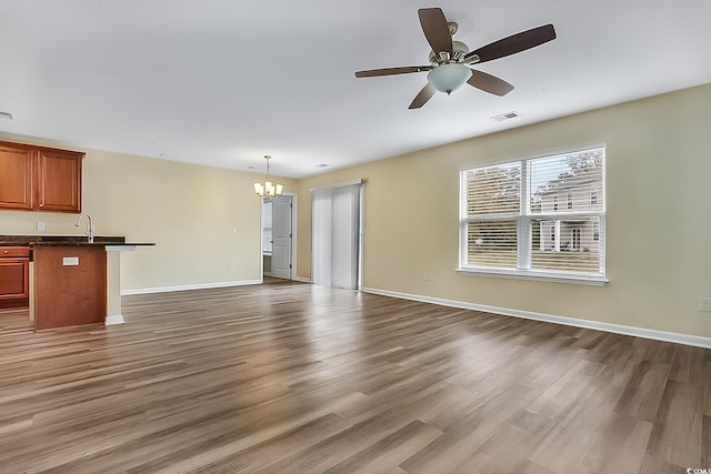 unfurnished living room with dark hardwood / wood-style flooring, ceiling fan with notable chandelier, and sink