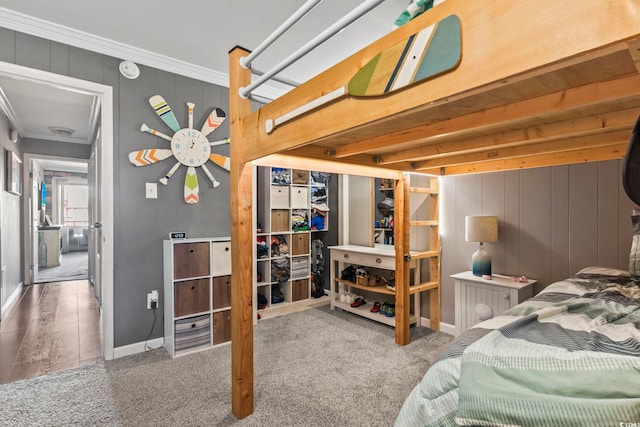 bedroom with beam ceiling, wood walls, carpet floors, and ornamental molding