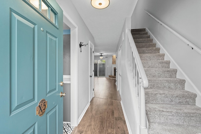 foyer with ceiling fan, dark hardwood / wood-style floors, and a brick fireplace