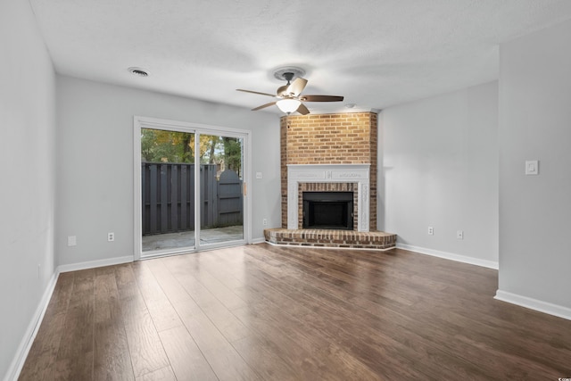 unfurnished living room with a fireplace, a textured ceiling, dark hardwood / wood-style flooring, and ceiling fan