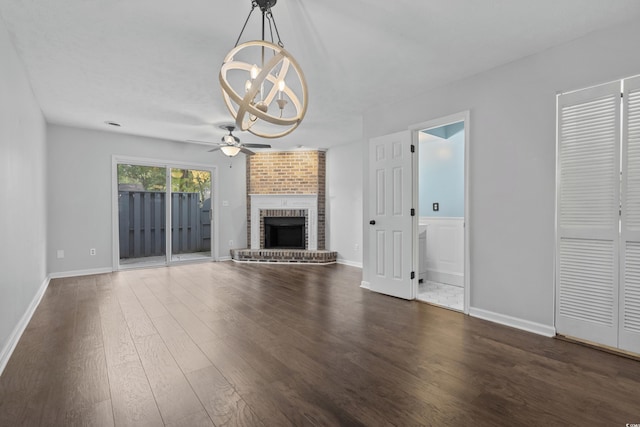 unfurnished living room with a fireplace, ceiling fan with notable chandelier, and dark hardwood / wood-style floors