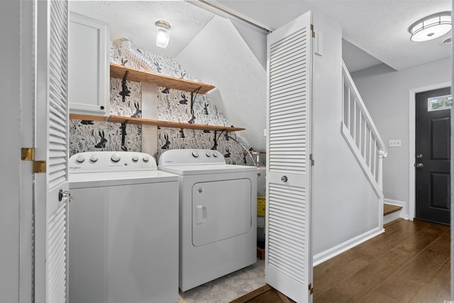 clothes washing area with cabinets, a textured ceiling, dark hardwood / wood-style floors, and washer and clothes dryer