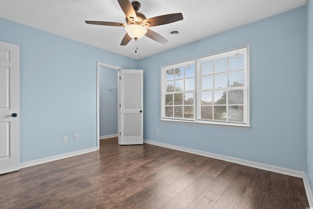 empty room with ceiling fan and dark wood-type flooring