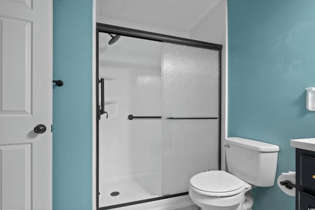 bathroom with a shower with door, vanity, and toilet