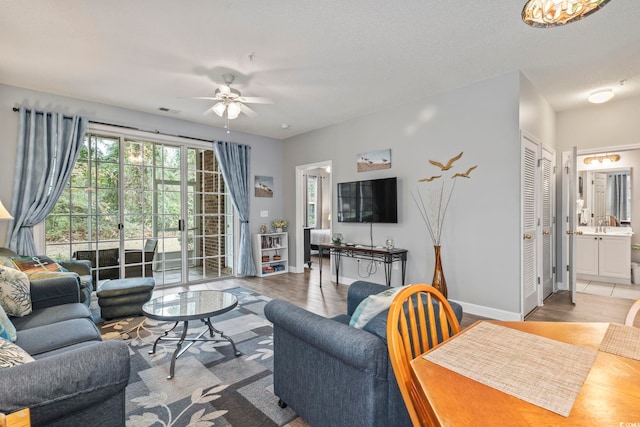 living room with ceiling fan, light hardwood / wood-style flooring, and a textured ceiling