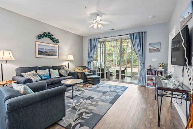 living room featuring ceiling fan, a textured ceiling, and hardwood / wood-style flooring