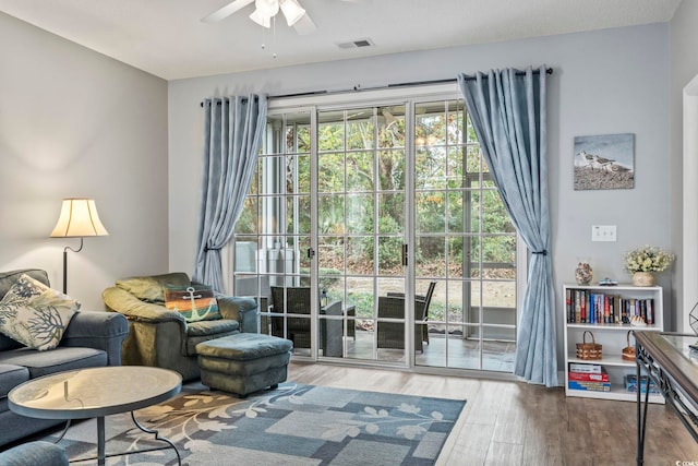 living area with a wealth of natural light, ceiling fan, and hardwood / wood-style flooring