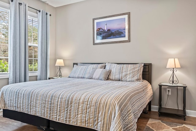 bedroom with dark hardwood / wood-style floors and multiple windows