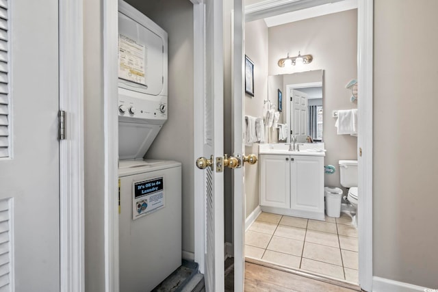 interior space featuring stacked washing maching and dryer, sink, and light tile patterned floors