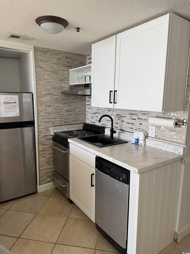 kitchen with white cabinets, appliances with stainless steel finishes, light tile patterned flooring, and sink