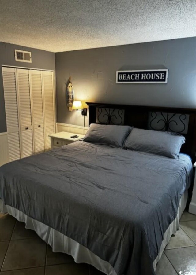 tiled bedroom featuring a textured ceiling and a closet