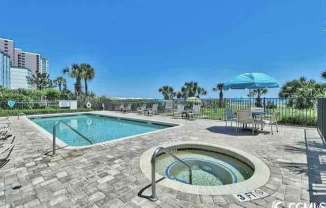 view of pool with a hot tub and a patio area