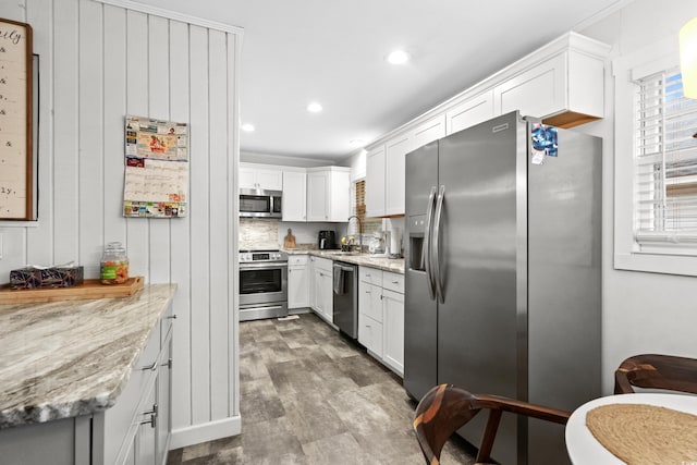 kitchen with white cabinets, light stone countertops, hardwood / wood-style floors, and appliances with stainless steel finishes