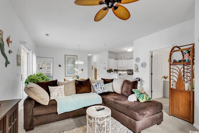 carpeted living room featuring ceiling fan with notable chandelier