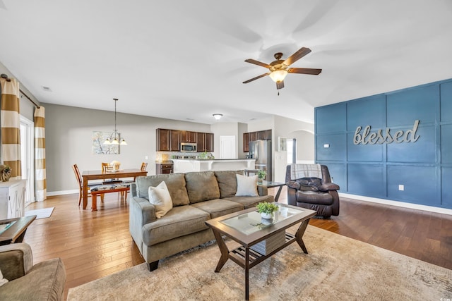 living room featuring ceiling fan with notable chandelier and light hardwood / wood-style flooring