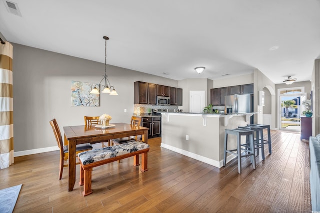 kitchen featuring appliances with stainless steel finishes, a breakfast bar, dark brown cabinetry, hardwood / wood-style flooring, and a center island