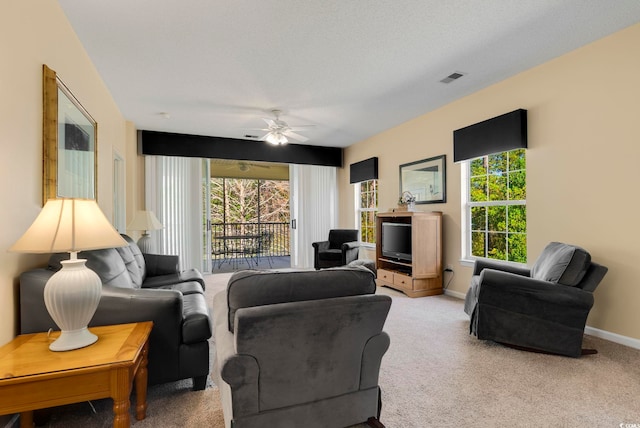 living area featuring visible vents, a ceiling fan, light carpet, a textured ceiling, and baseboards