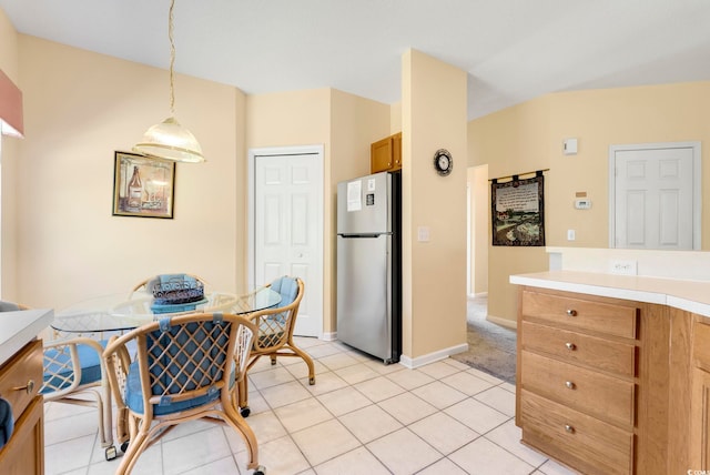 kitchen featuring light tile patterned floors, brown cabinets, decorative light fixtures, freestanding refrigerator, and light countertops