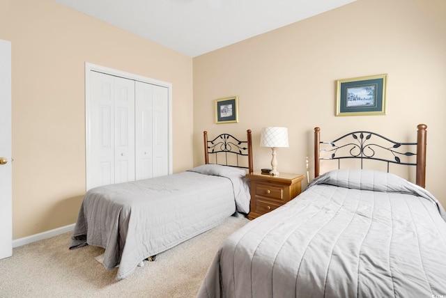 carpeted bedroom featuring a closet and baseboards