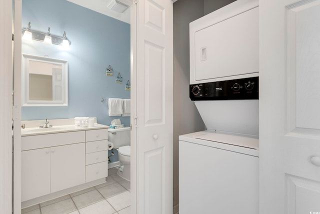 clothes washing area featuring light tile patterned floors, laundry area, visible vents, stacked washing maching and dryer, and a sink