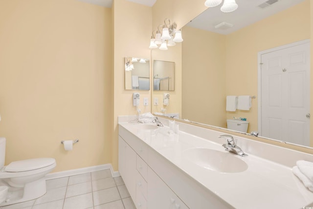 bathroom featuring baseboards, visible vents, toilet, tile patterned flooring, and a sink